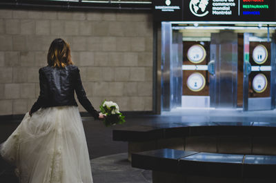 Rear view of bride holding bouquet in subway