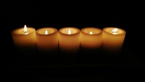 Close-up of illuminated tea light candles in darkroom