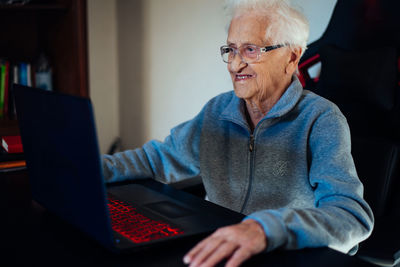 Smiling senior woman using laptop while sitting at home