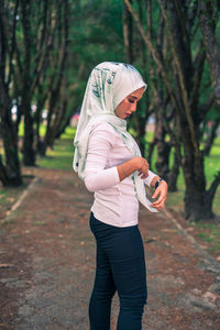 Side view of woman with umbrella against trees