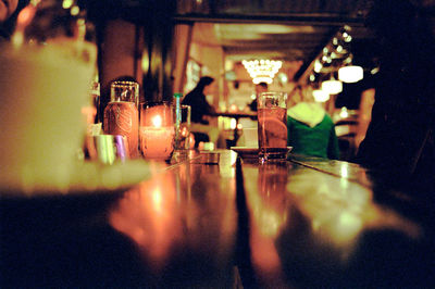 Close-up of illuminated glasses on table in restaurant