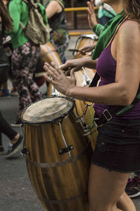 Midsection of woman playing musical equipment on street in city