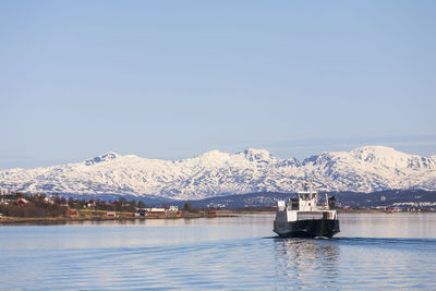 Ferry in a norwegian fjord with snow capped mountains in the spring