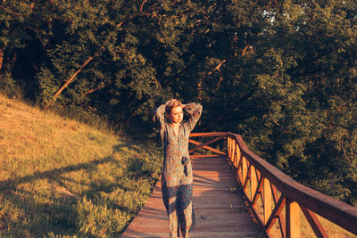 Woman standing on bridge at sunset