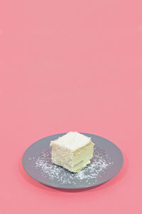 Close-up of cake on plate against pink background