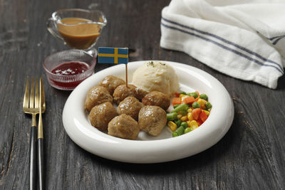 Meatballs with creamy mashed potatoes and sweet red sauce decorated by swedish flag