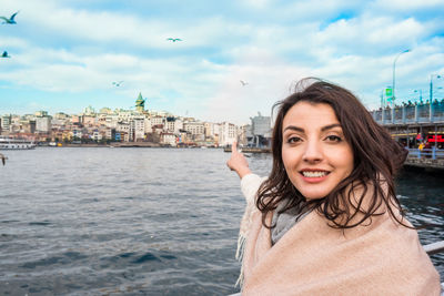 Portrait of smiling woman in city against sky