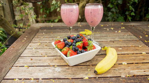 High angle view of fruits by drink in glass on table