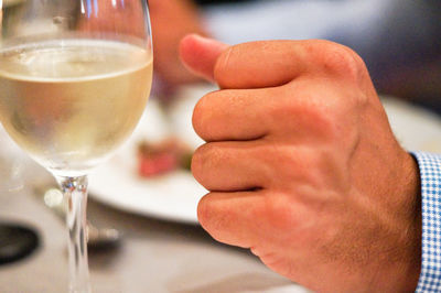 Close-up of hand by glass of drink