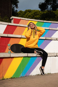 Portrait of a cheerful woman with a skateboard on colorful stairs