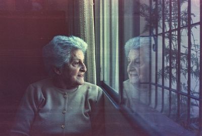 Senior woman looking through window at home