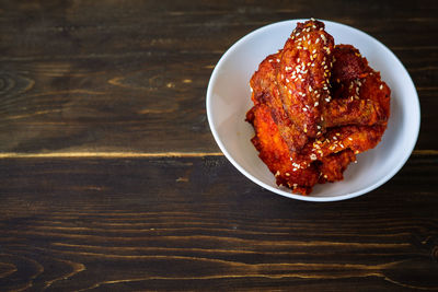 Fried chicken in a spicy sauce and sesame seeds. food korean cuisine on a wooden background.