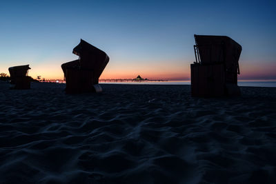 Silhouette beach by sea against sky during sunset
