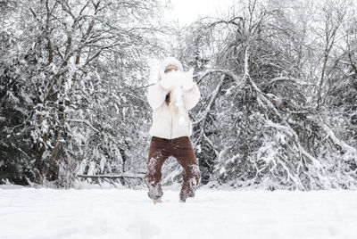 A young girl throws snow in the winter forest.