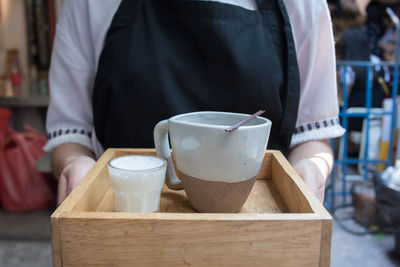 Midsection of man with drink standing on table