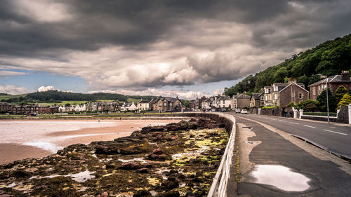 Road by sea and city against sky