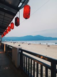 Lanterns hanging on beach against sky