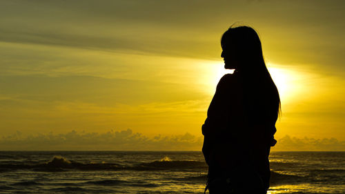 Silhouette man standing on beach during sunset