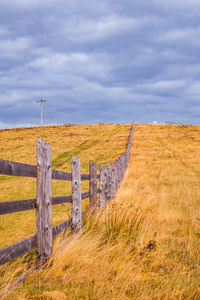 Wooden fence on field against sky