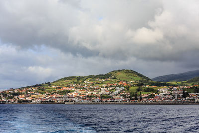 Scenic view of sea by townscape against sky