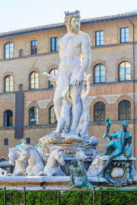 Statue by fountain against building in city