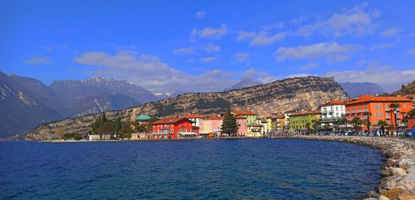 Buildings by sea against blue sky