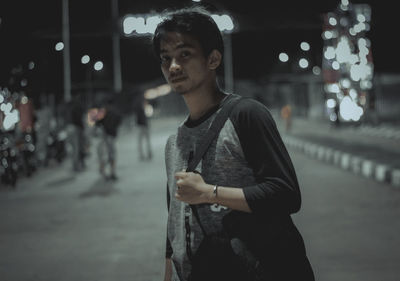 Young man looking away in city at night