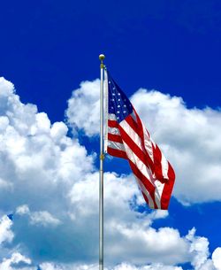 Low angle view of american flag against cloudy blue sky