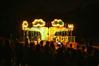 Illuminated carousel in amusement park at night