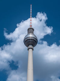 Low angle view of communications tower and building against sky