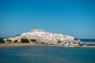 Scenic view of sea and buildings against clear blue sky