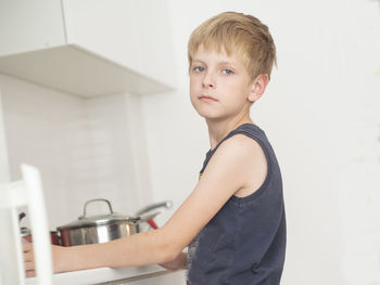 Side view portrait of boy standing in kitchen at home