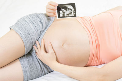 Midsection of pregnant woman holding baby