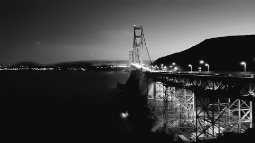 Illuminated bridge over river at night