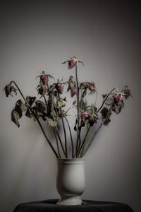 Close-up of white flower vase on table against wall at home