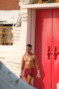 Full length of shirtless man standing against built structure