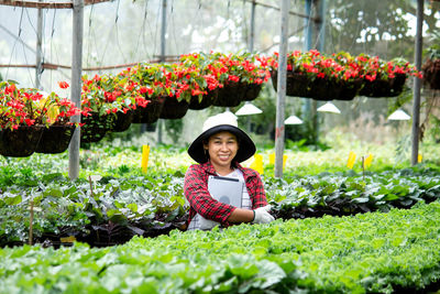 Portrait of smiling woman wearing hat standing amidst plants