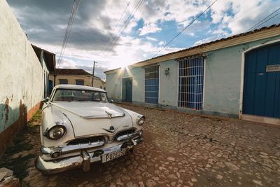 Cars on road by buildings in city against sky