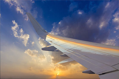 Cropped image of airplane wing against sky during sunset