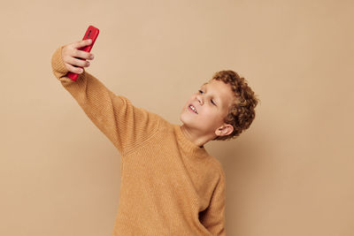 Boy taking selfie against beige background