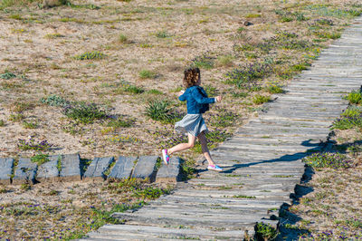 Full length of girl running on boardwalk