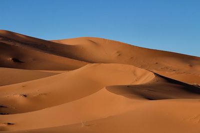 Scenic view of desert against clear blue sky