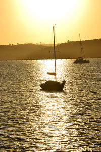 Silhouette sailboats in sea against sky during sunset