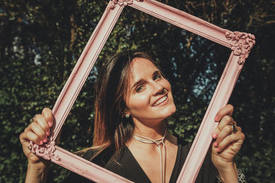 Portrait of smiling young woman holding picture frame