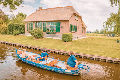 Family on boat in canal against house