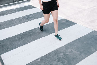 Low section of man walking on zebra crossing