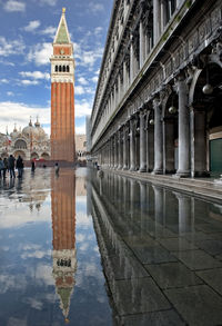 Reflection of tower on puddle in piazza san marco against sky