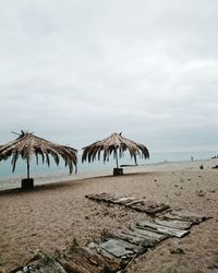 Deck chairs on beach against sky