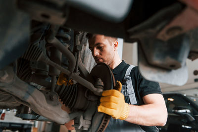 Professional service. man in uniform is working in the auto service.