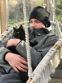 Man with cat relaxing on swing